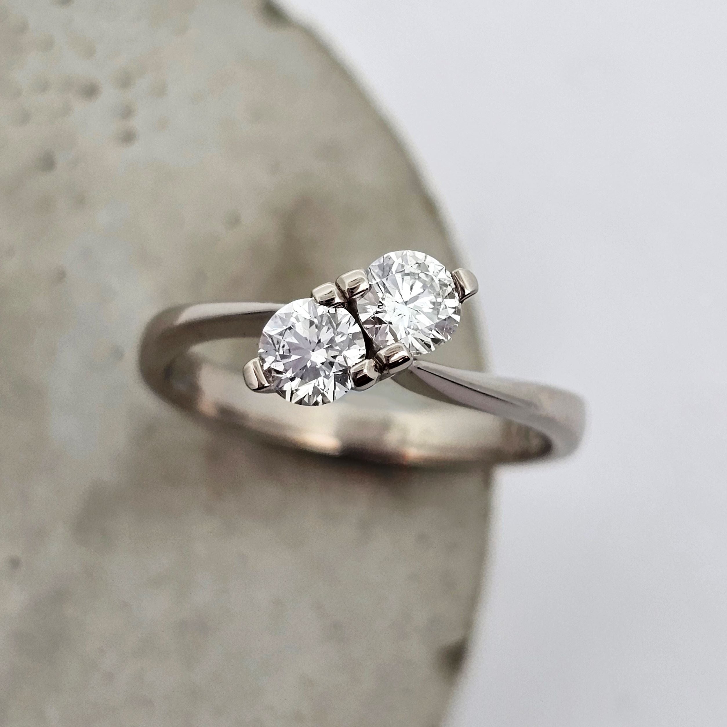 9ct white gold ladies engagement ring with two sparkling round white diamonds claw set side by side on an angle, nestled into a ring with sweeping curved shoulders.