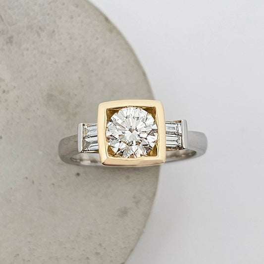 Platinum and 18ct yellow gold ring featuring a large sparkling round white diamond in a square yellow gold setting with channel set baguette white diamonds.