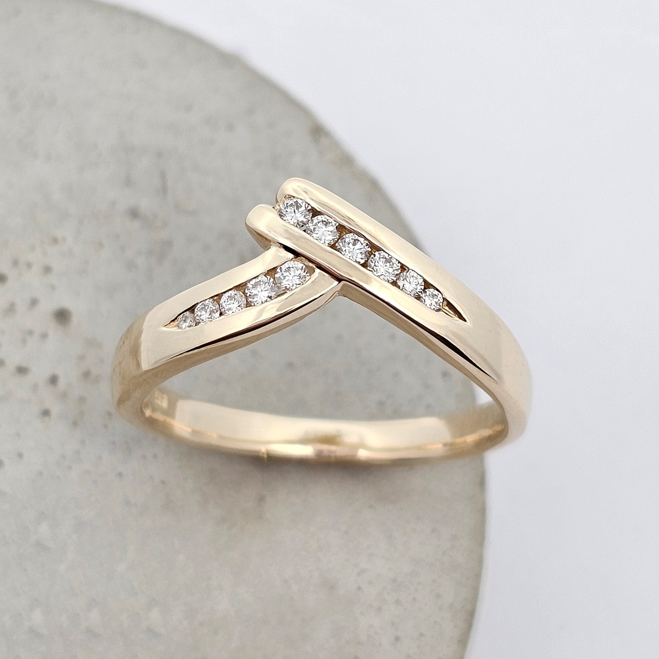 Yellow gold wedding ring with crossover design set with sparkling white diamonds.
