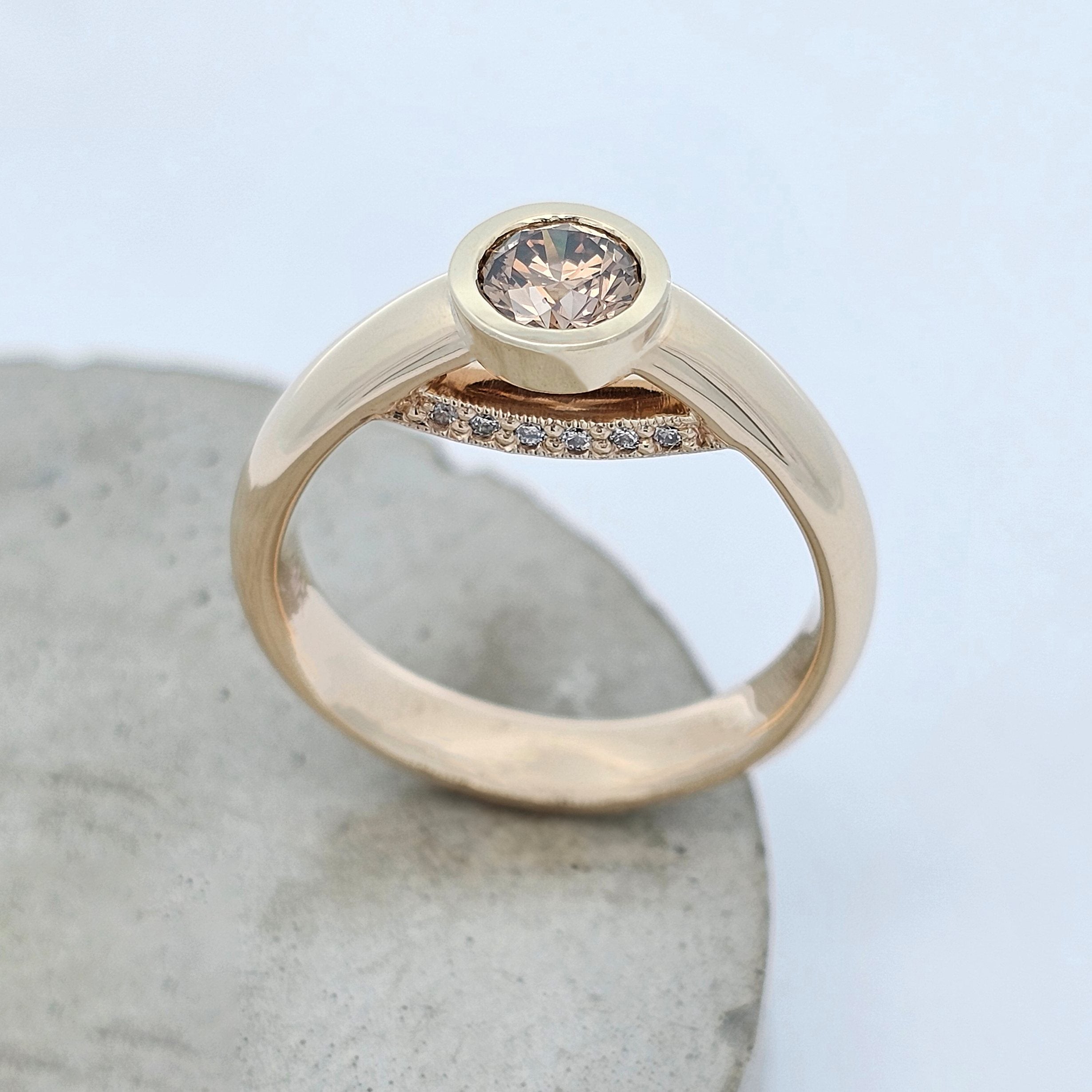 Yellow gold diamond ring featuring a bezel-set Argyle chocolate diamond with a hidden row of white diamonds beneath the centre stone.