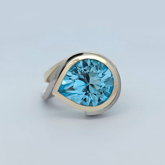 9ct yellow and white gold ladies dress ring with large pear shaped sky blue topaz rub set in curved asymmetrical design.