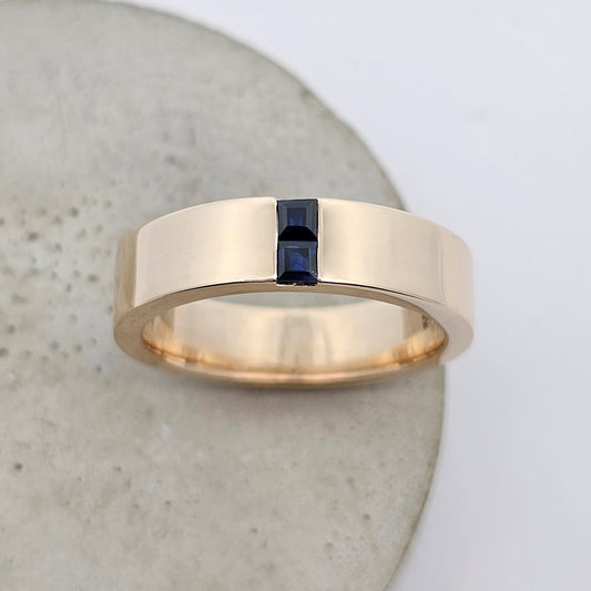 Contemporary men’s wedding ring in yellow gold with two carre-cut Australian sapphire channel set north-south in centre