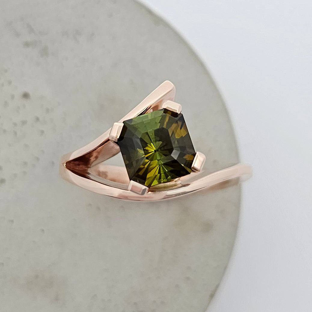 9ct rose gold ladies dress ring featuring a square emerald cut green tourmaline in an asymmetrical split band design.