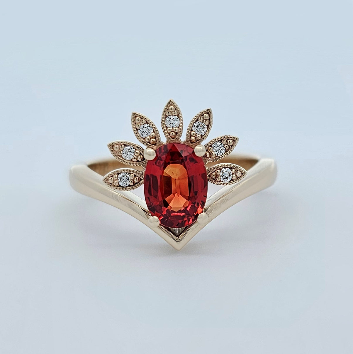 9ct yellow gold ladies coloured gemstone ring with claw set oval orange sapphire and a fan of brilliant white round diamonds.