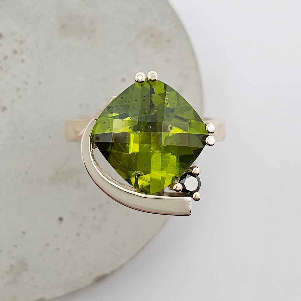 9ct yellow and white gold ladies dress ring with a large cushion shaped green peridot claw set with a black diamond.