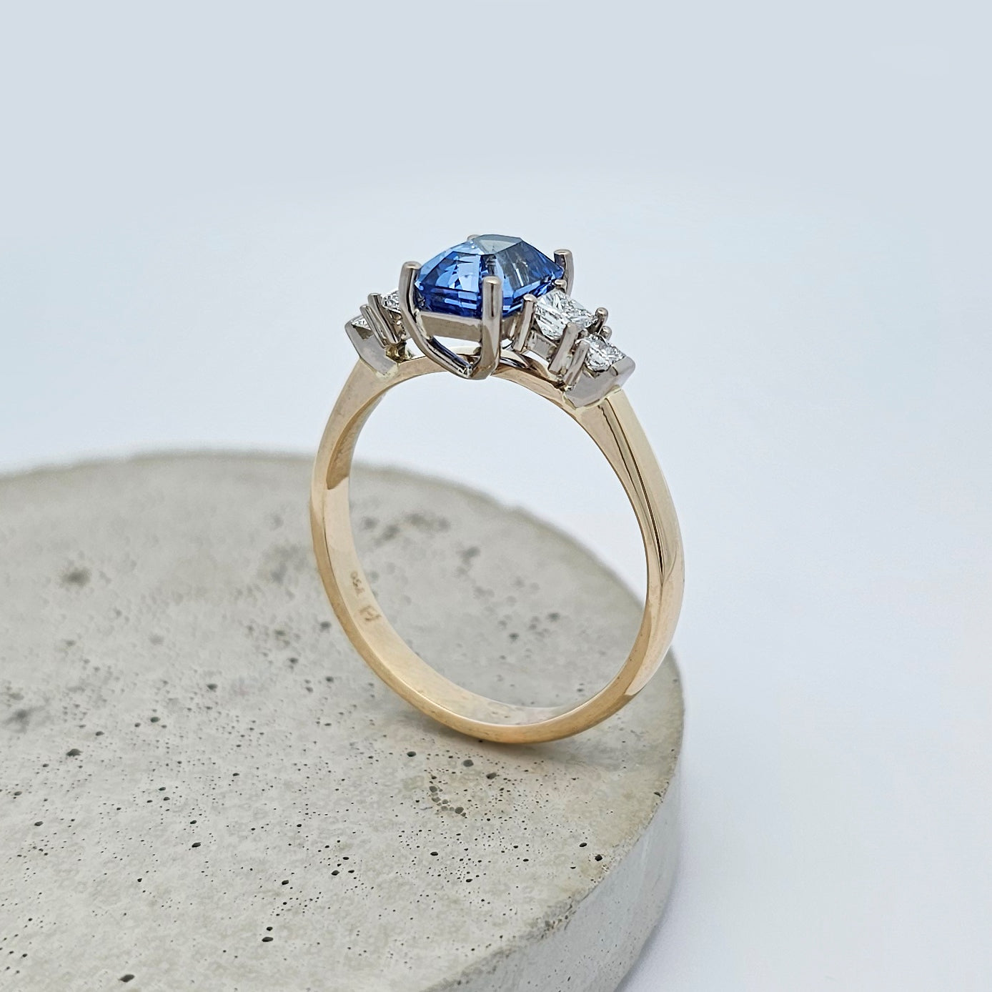 9ct yellow and white gold ladies five stone engagement or dress ring with bright blue emerald cut sapphire between claw set princess cut diamonds.