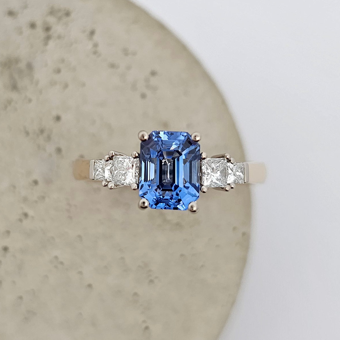 9ct yellow and white gold ladies five stone engagement or dress ring with bright blue emerald cut sapphire between claw set princess cut diamonds.