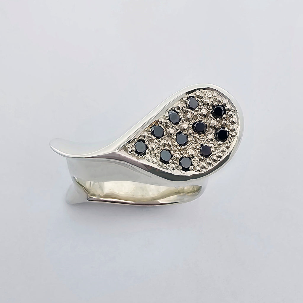 9ct white gold ladies dress ring inspired by the shape of a sea-shell with flowing curves and undulations, pave set with round black diamonds.
