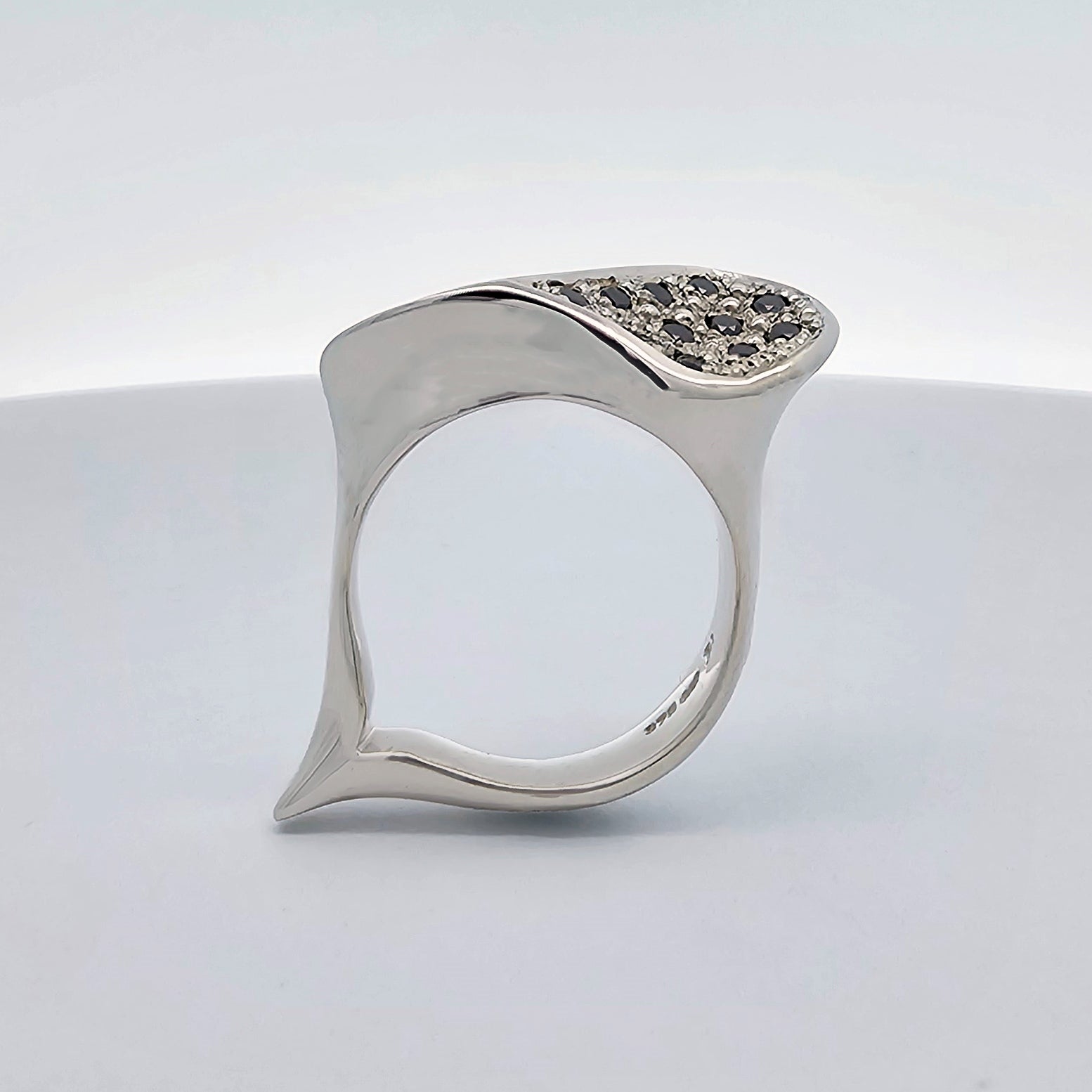 9ct white gold ladies dress ring inspired by the shape of a sea-shell ring with flowing curves and undulations, pave set with round black diamonds.