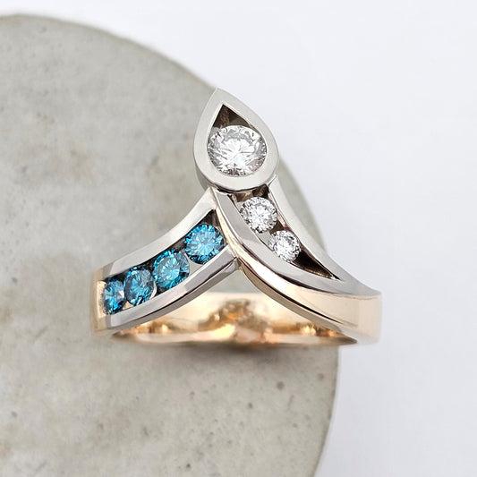 9ct yellow and white gold ladies dress ring with sweeping arms channel set with sparkling white and blue diamonds finished with a large round white diamond set in a pear shape setting.