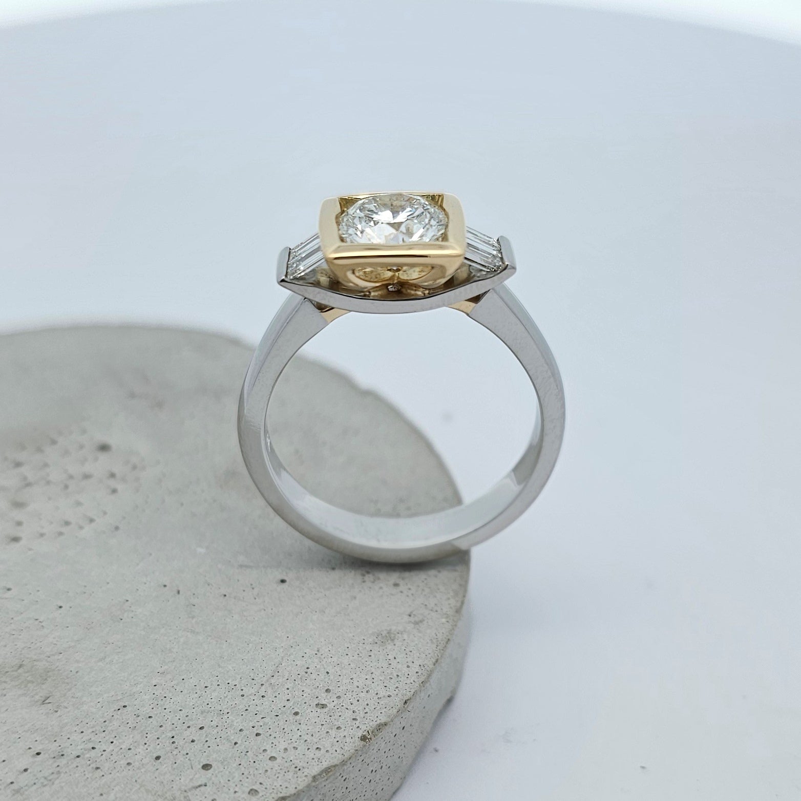 Platinum and 18ct yellow gold ring featuring a large sparkling round white diamond in a square yellow gold setting with channel set baguette white diamonds.