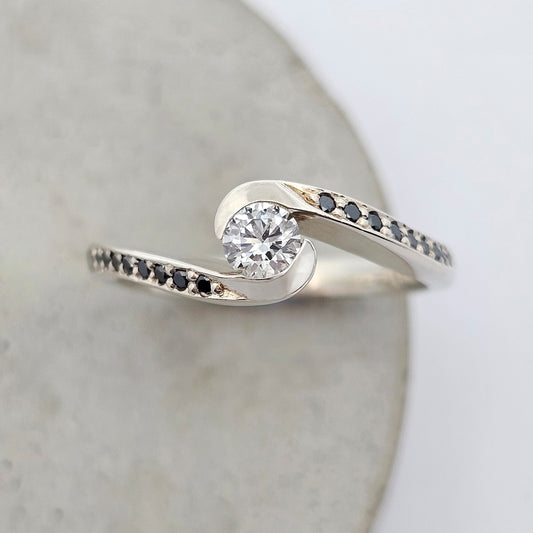 round diamond ring; white gold diamond ring; white gold engagement ring; cross over diamond ring; shaped engagement ring; black diamond ring; natural diamond ring; curved engagement ring; diamond anniversary ring; diamond dress ring; black diamond dress ring; black and white diamond engagement ring