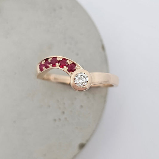 9ct rose gold ladies ring with one full rub over set round white diamond and a curved row of bead set red ruby.