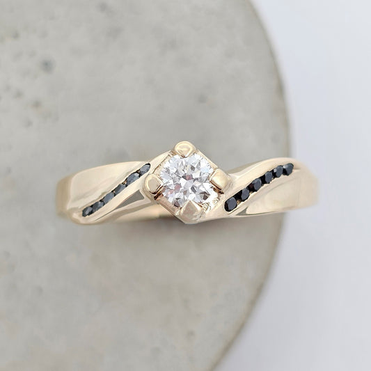 yellow gold claw-set diamond engagement ring with black diamond shoulder accent stones