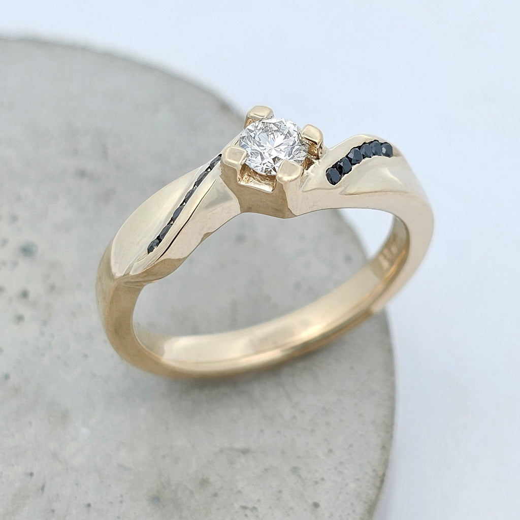 yellow gold claw-set diamond engagement ring with black diamond shoulder accent stones 