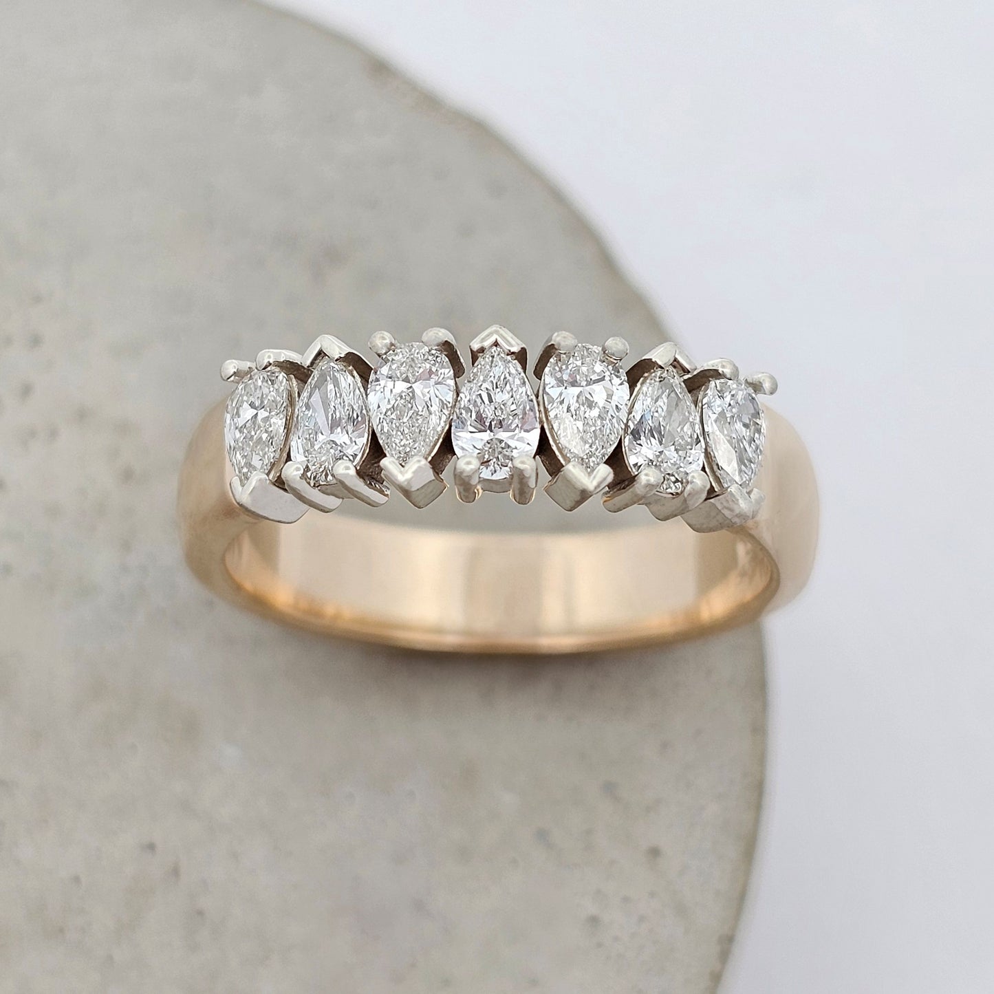 Diamond ring featuring pear-shaped diamonds in classic claw settings, forming a continuous row of brilliance.