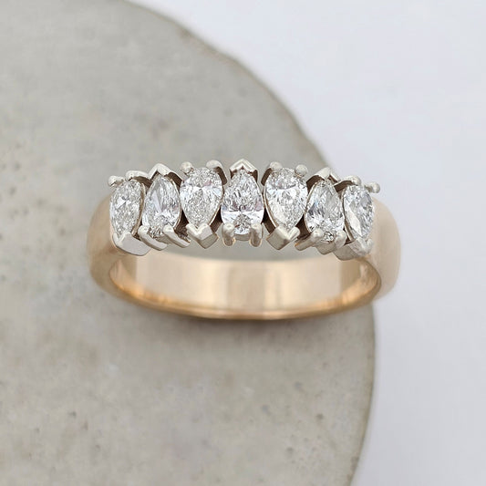Diamond ring featuring pear-shaped diamonds in classic claw settings, forming a continuous row of brilliance.