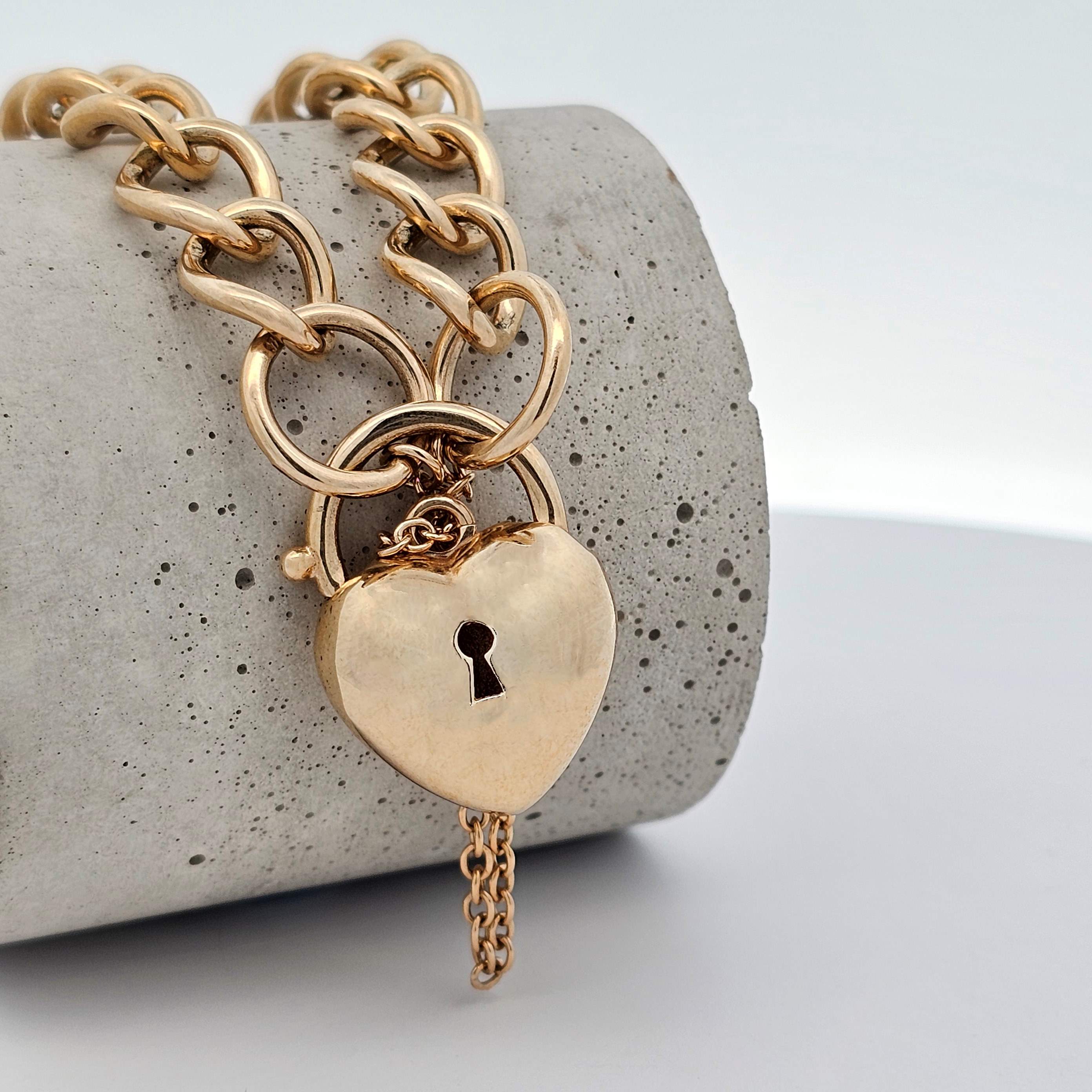 yellow gold heavy curb link bracelet with puff heart padlock and safety chain