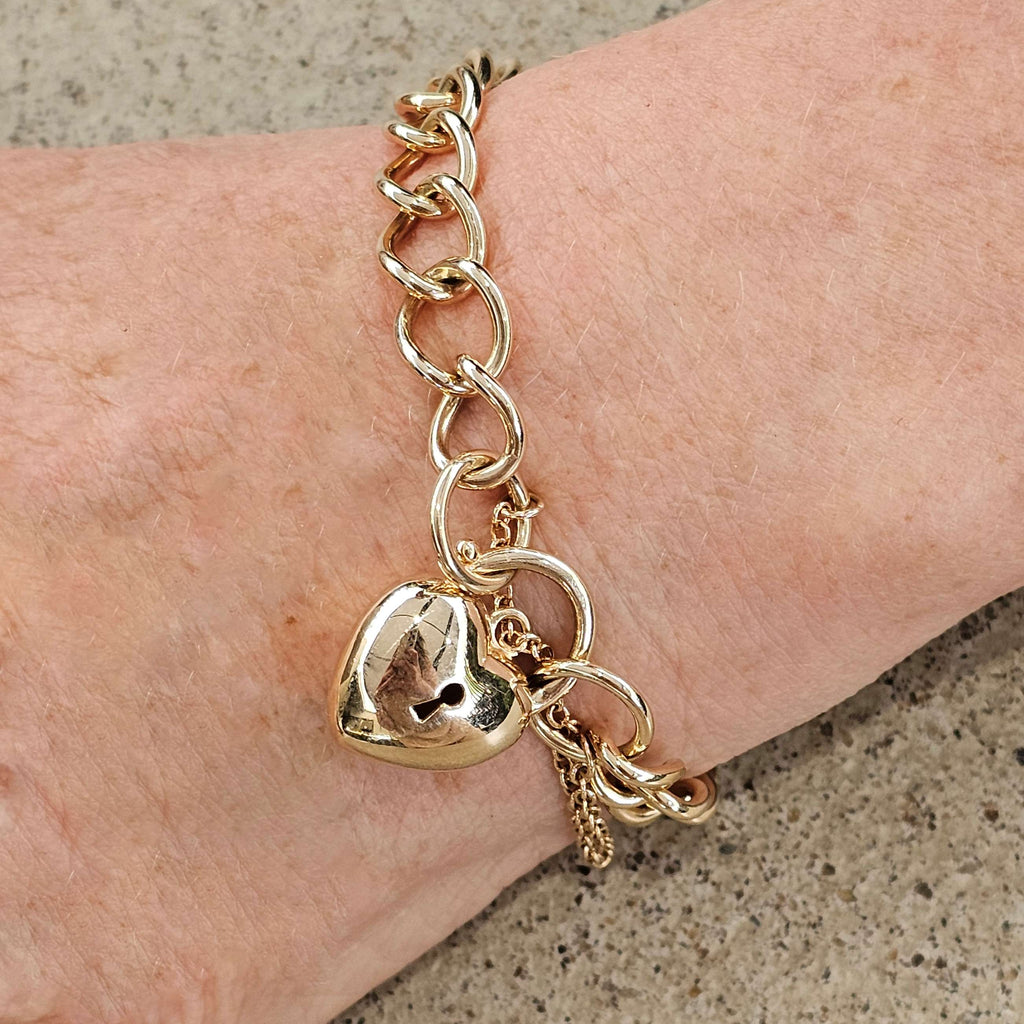 yellow gold heavy curb link bracelet with puff heart padlock and safety chain on wrist