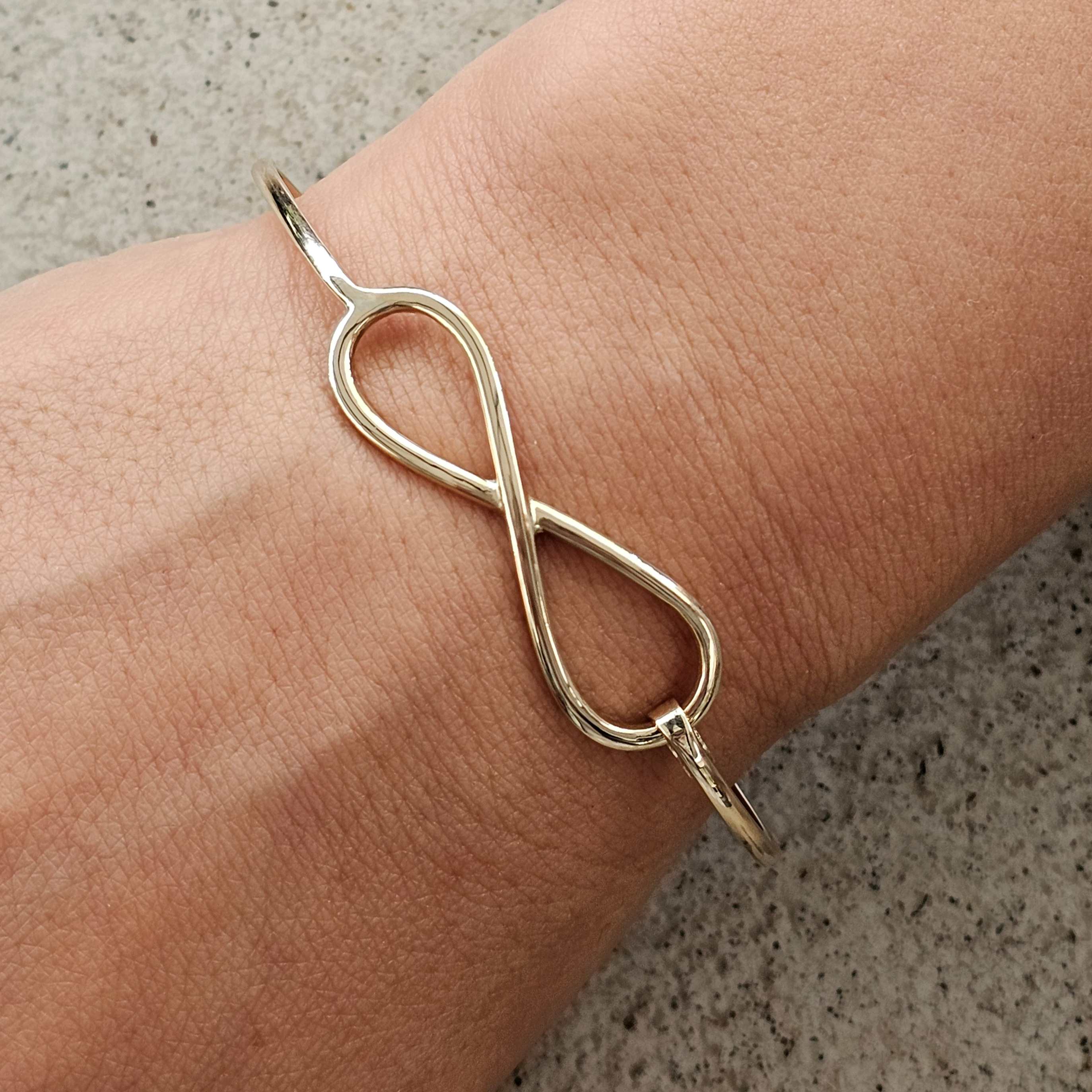 Handcrafted yellow gold infinity bangle design shown on wrist