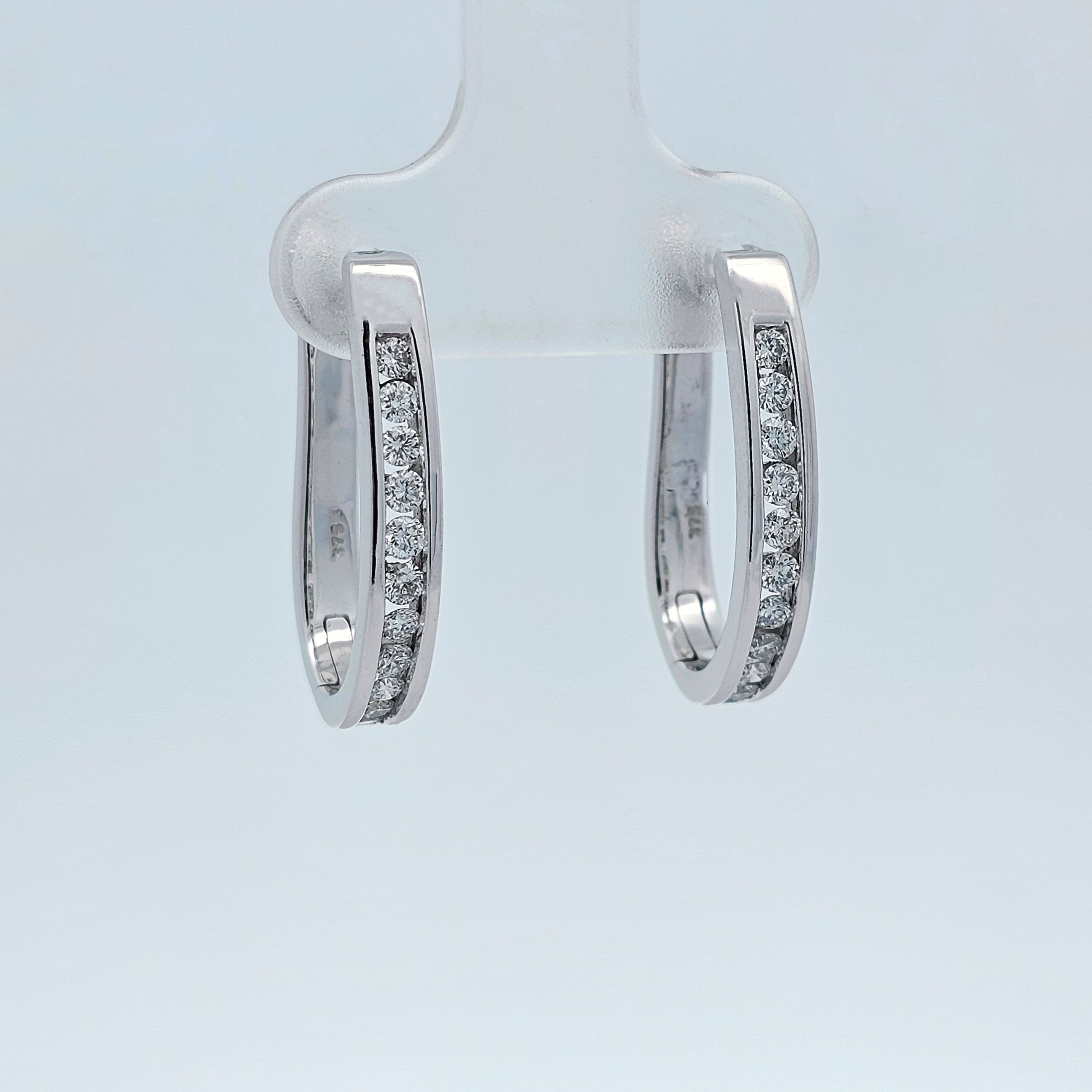 Pair of white gold diamond huggie earrings, channel-set with round brilliant diamonds in a sleek, curved design