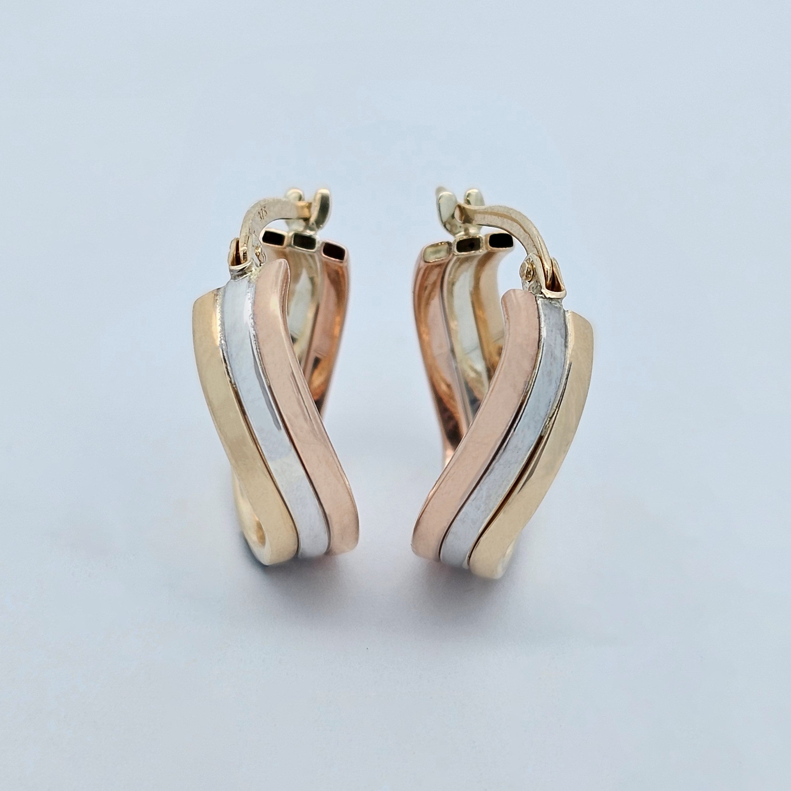 Tri-gold hoop earrings with flowing yellow, white and rose gold curved bands.
