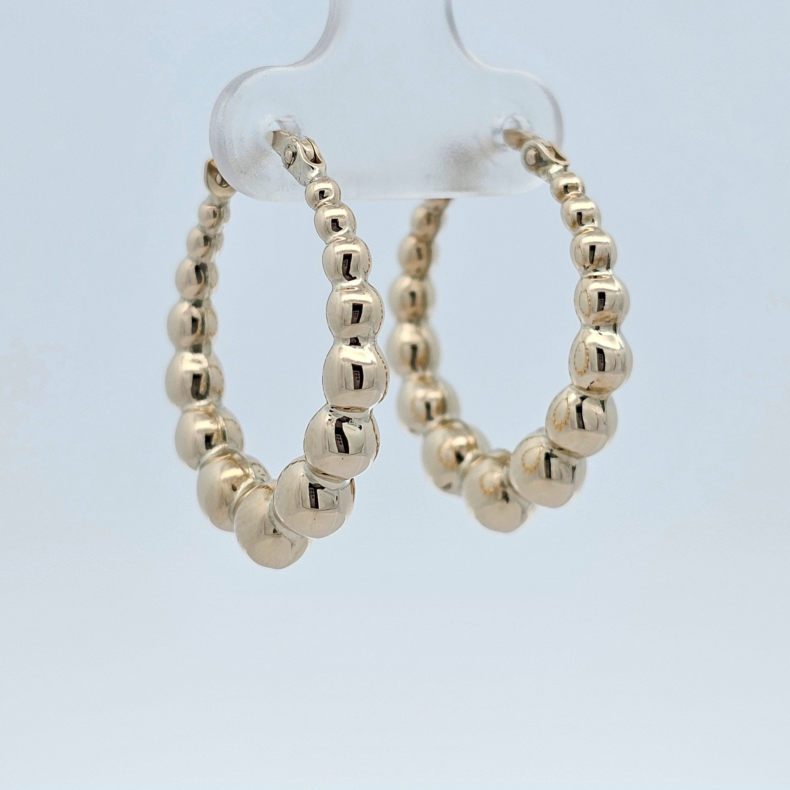 Polished gold beaded crescent hoop earrings featuring rounded bead detailing
