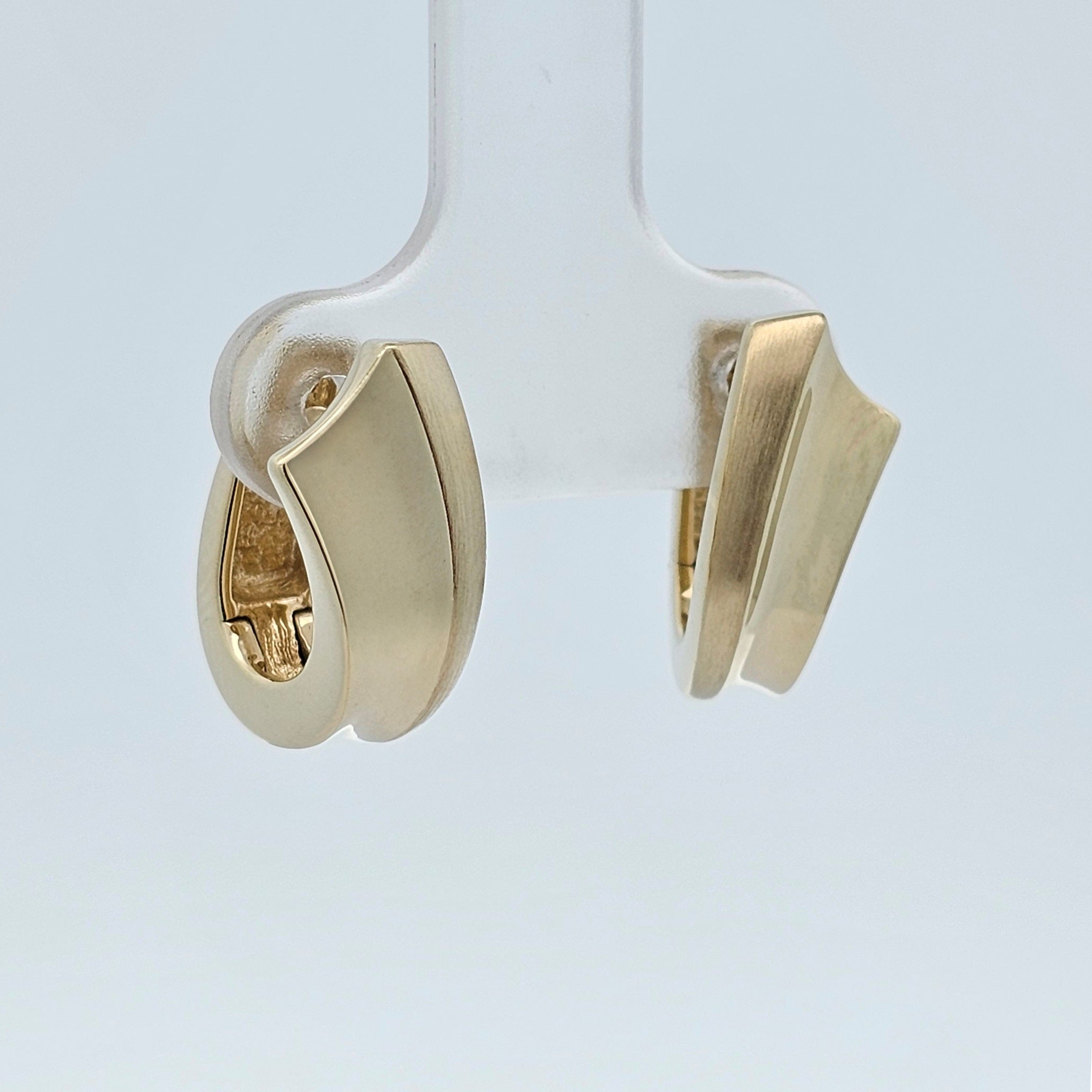 Yellow gold sculptural huggie hoop earrings with a flared, curved design, inspired by movement and light