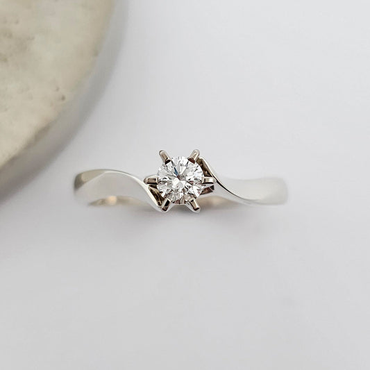 Classic 9ct white gold ladies solitaire engagement ring, with a sparkling round white diamond, claw set between the sweeping curves of knife edge shoulders.