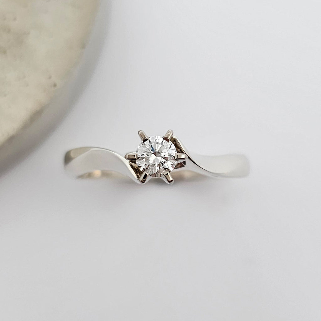 Classic 9ct white gold ladies solitaire engagement ring, with a sparkling round white diamond, claw set between the sweeping curves of knife edge shoulders.