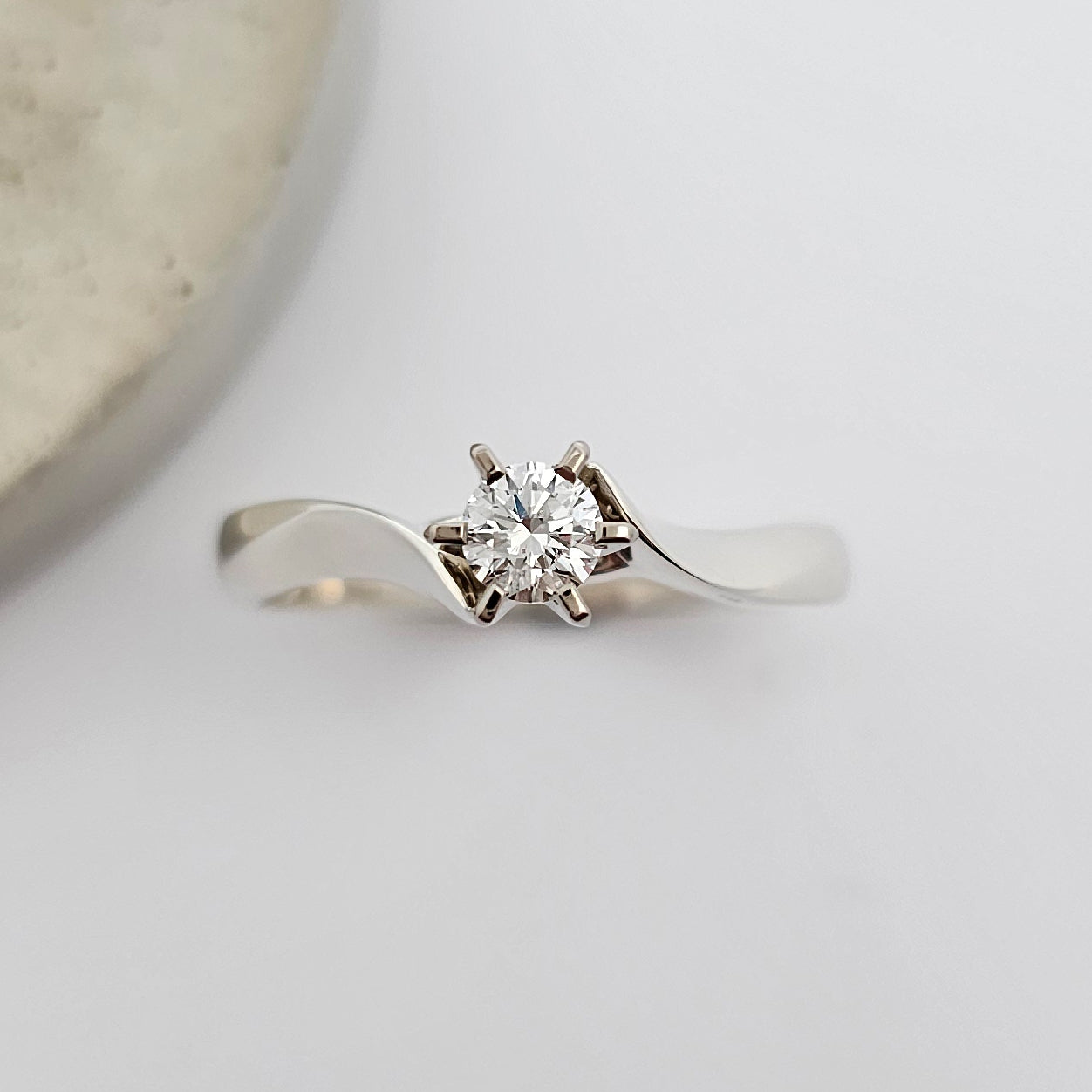 Classic 9ct white gold ladies solitaire engagement ring, with a sparkling round white diamond, claw set between the sweeping curves of knife edge shoulders.