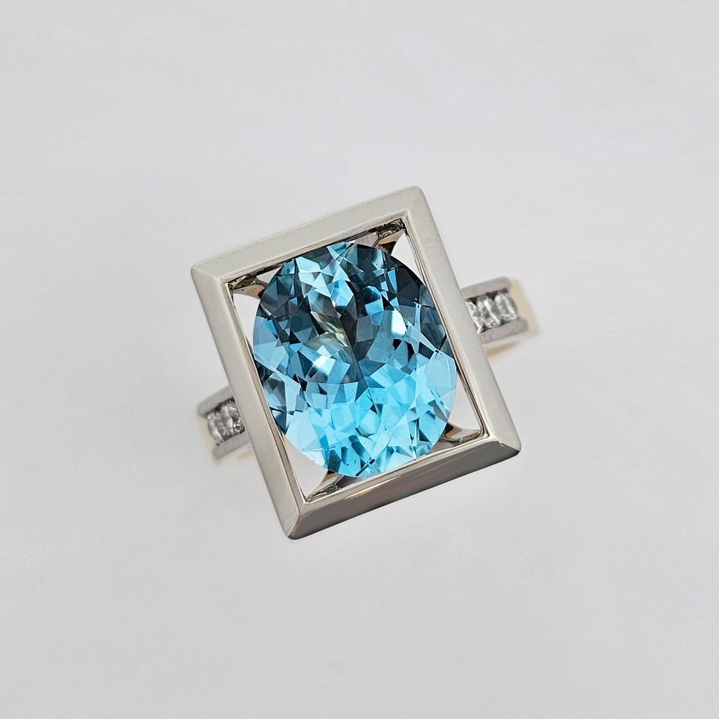 18ct yellow and 9ct white gold ladies dress ring with a large oval aquamarine set in a white gold setting with round brilliant white diamonds channel set in each shoulder.