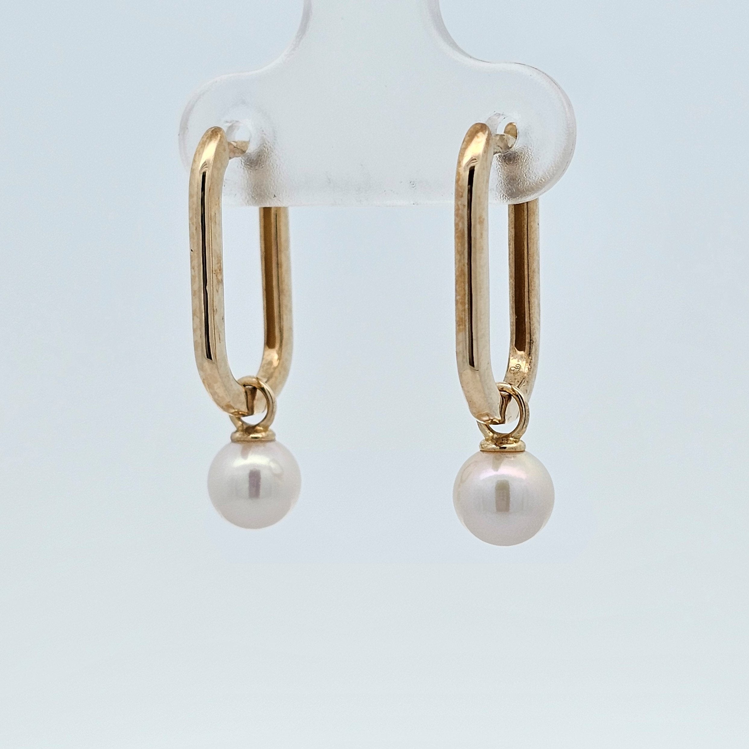 Yellow gold huggie earrings with removable pearl drop charm, shown worn with pearl attached.
