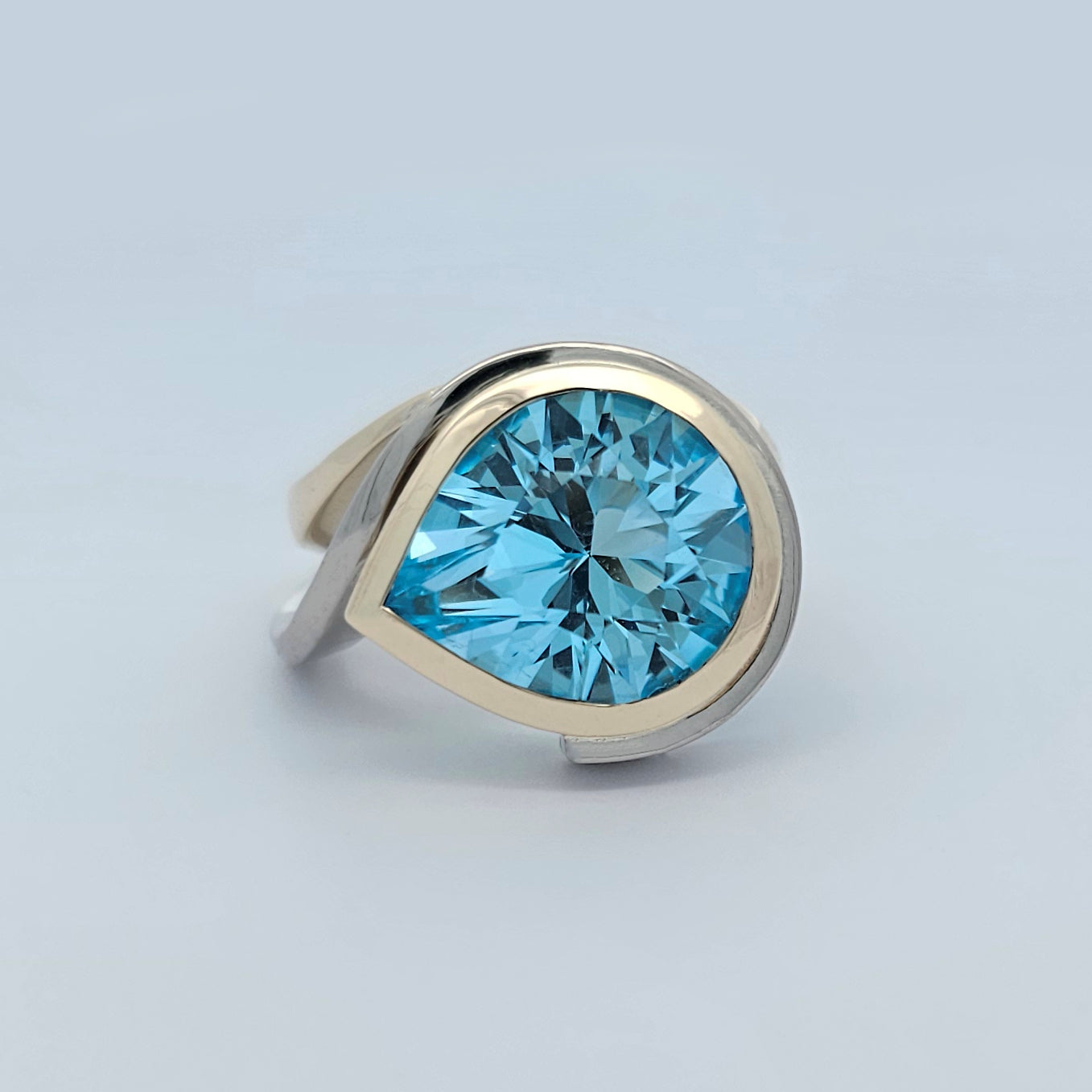 9ct yellow and white gold ladies dress ring with large pear shaped sky blue topaz rub set in curved asymmetrical design.
