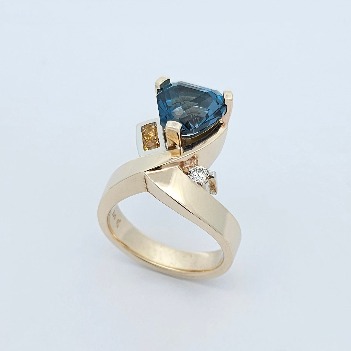 9ct yellow and white gold ladies dress ring with a trilliant cut blue topaz claw set, yellow citrine channel set in to one shoulder and a claw set bright white diamond.
