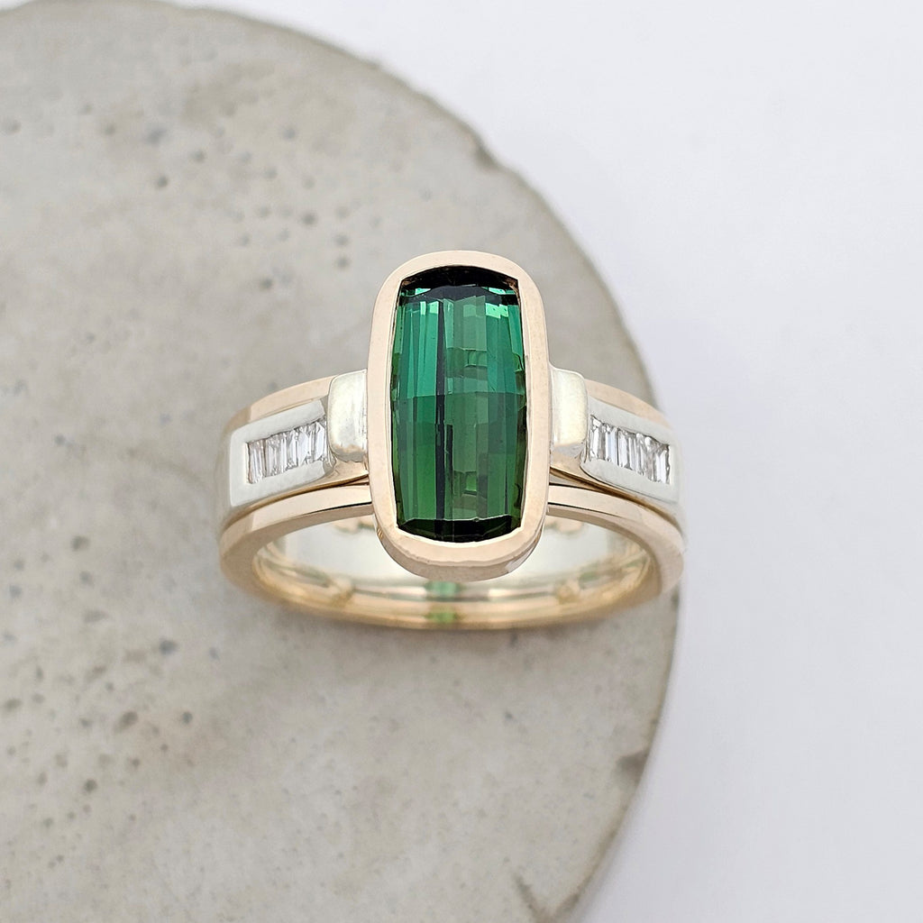 Elongated green tourmaline ring with baguette diamond accents in a contemporary white and yellow gold design.