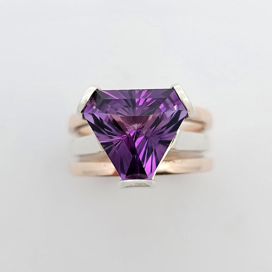 9ct rose and white gold ladies dress ring  featuring a deep purple trilliant cut amethyst claw set above three bands of gold.