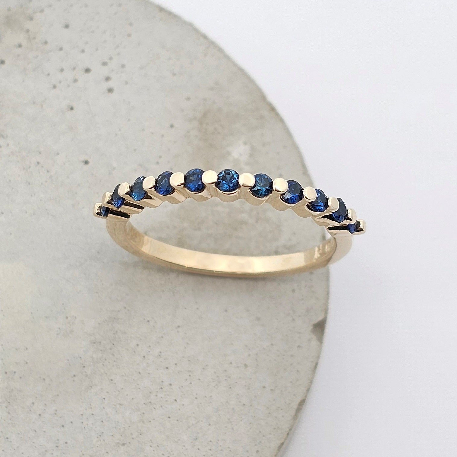 9ct yellow gold ladies straight wedding band with claw set round fine blue sapphires.