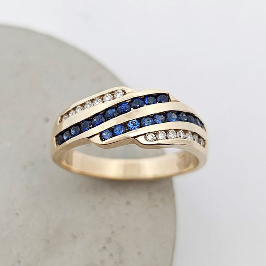 9ct yellow gold ladies ring with two rows of channel set round fine blue sapphire and two rows of sparkling round channel set diamonds.