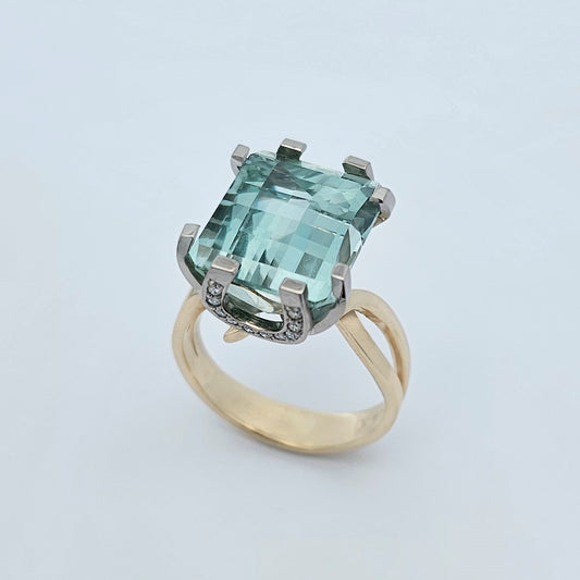 9ct yellow and white gold ladies dress ring featuring an extra large checker board cut aquamarine with round white diamonds set into horseshoe shaped side details.
