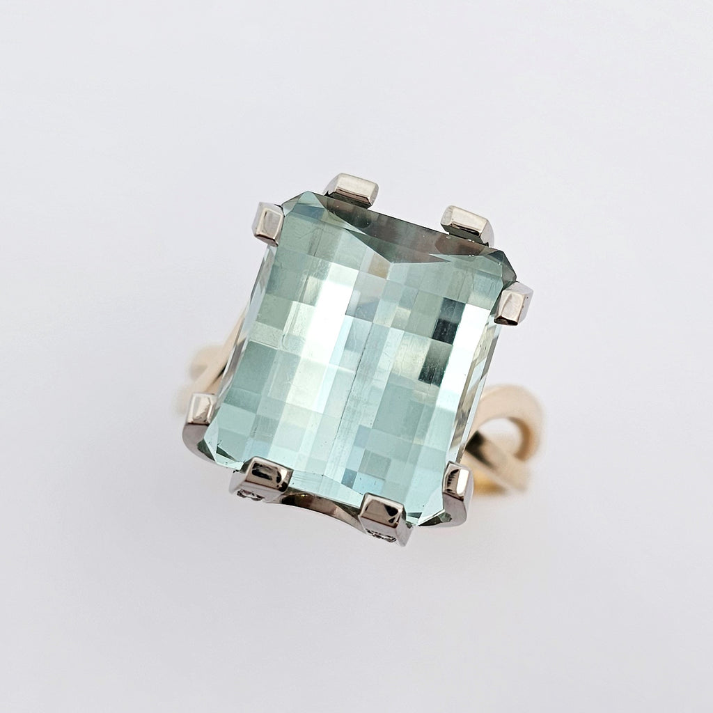 9ct yellow and white gold ladies dress ring featuring an extra large checker board cut aquamarine with round white diamonds set into horseshoe shaped side details.