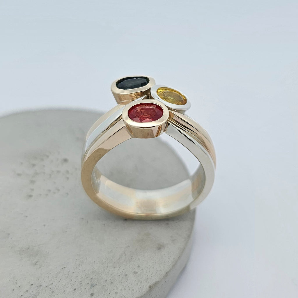 sapphire ring; three stone sapphire ring; natural sapphire ring; orange sapphire ring; blue sapphire ring; yellow sapphire ring; sapphire dress ring; sapphire cocktail ring; white gold and yellow gold sapphire ring; two tone sapphire ring; easy wear sapphire ring; sapphire engagement ring; curved sapphire ring; handmade sapphire ring; sapphire wedding ring; unique sapphire ring; 45th wedding anniversary; 45th wedding anniversary ring; September birthstone; September birthstone ring; celebration ring