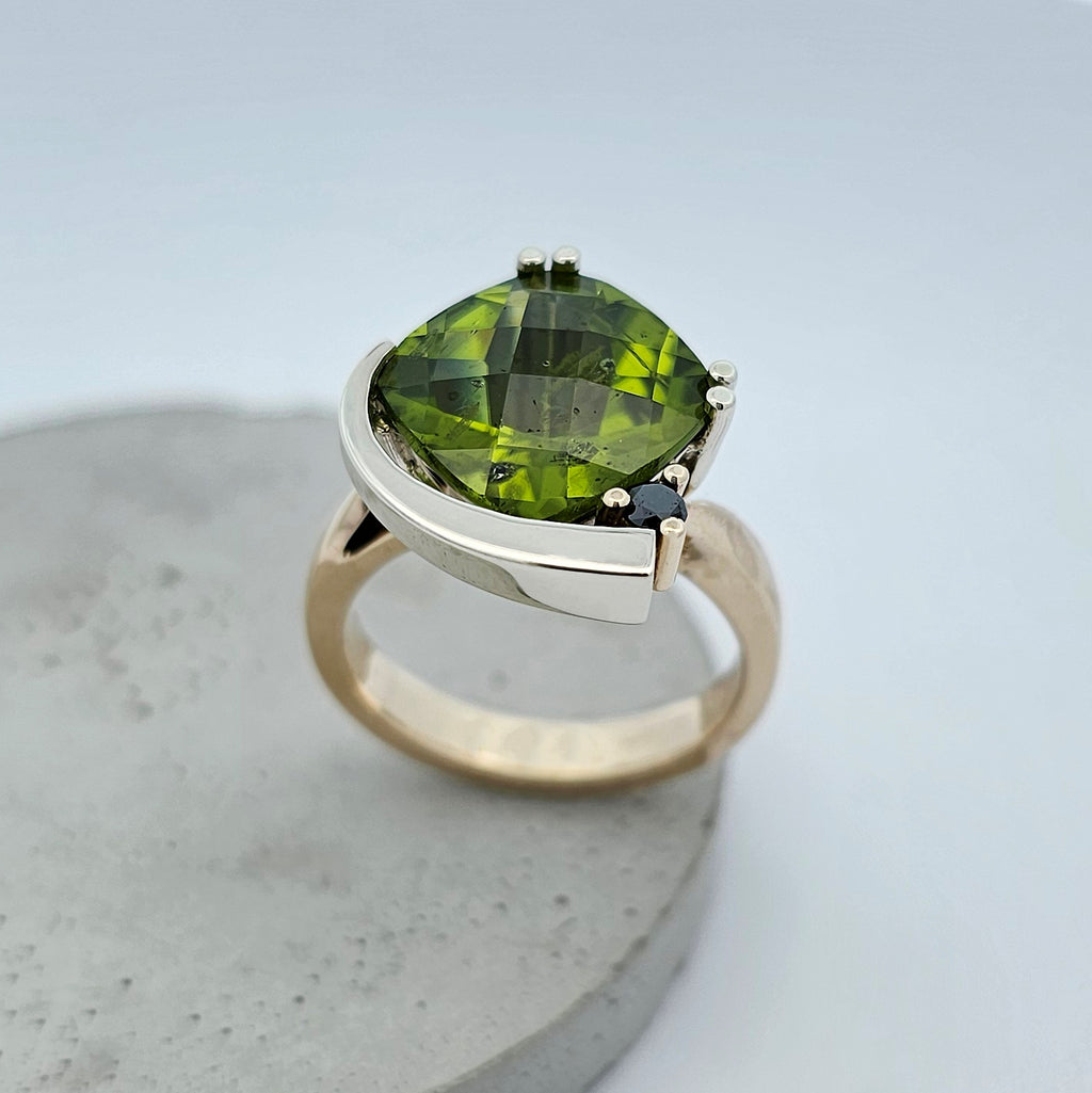 9ct yellow and white gold ladies dress ring with a large cushion shaped green peridot claw set with a black diamond.