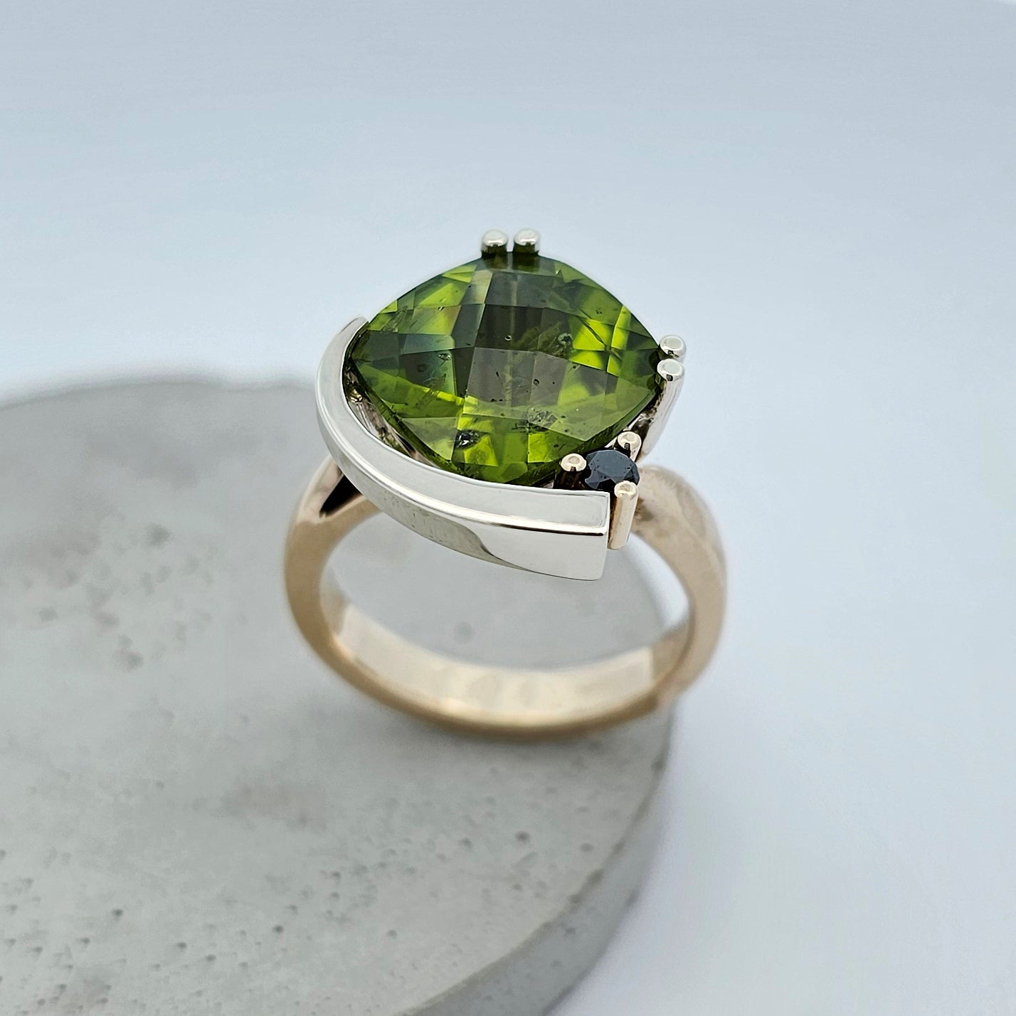 9ct yellow and white gold ladies dress ring with a large cushion shaped green peridot claw set with a black diamond.