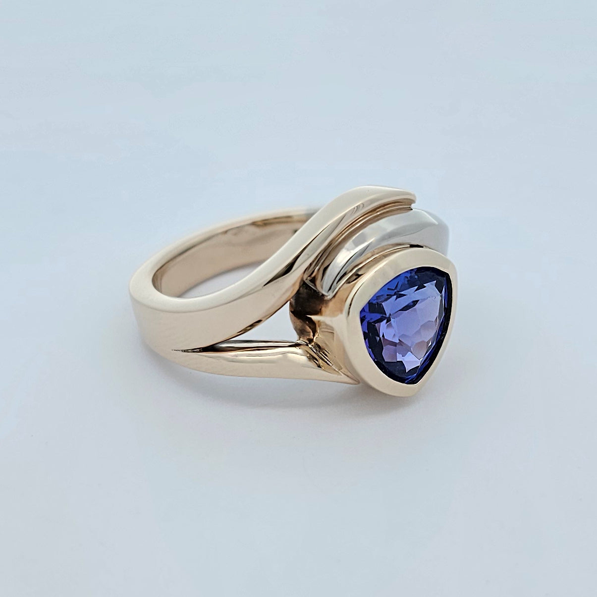 9ct yellow and white gold ladies dress ring with a trilliant cut rub set tanzanite in a curved asymmetrical design.