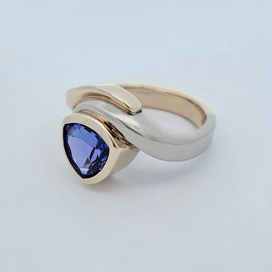 9ct yellow and white gold ladies dress ring with a trilliant cut rub set tanzanite in a curved asymmetrical design.