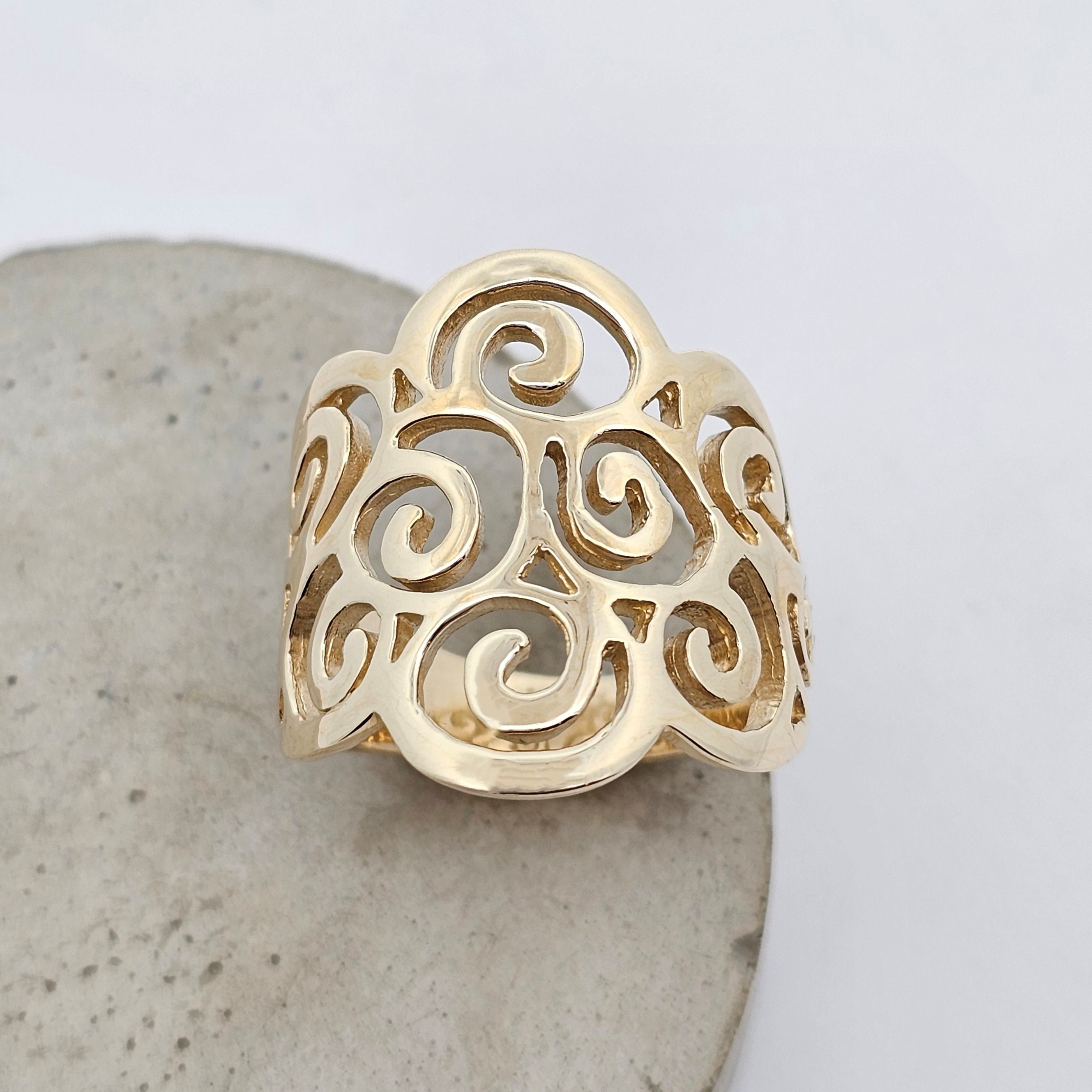 Koru-pattern gold ring with open lace-style swirling details.