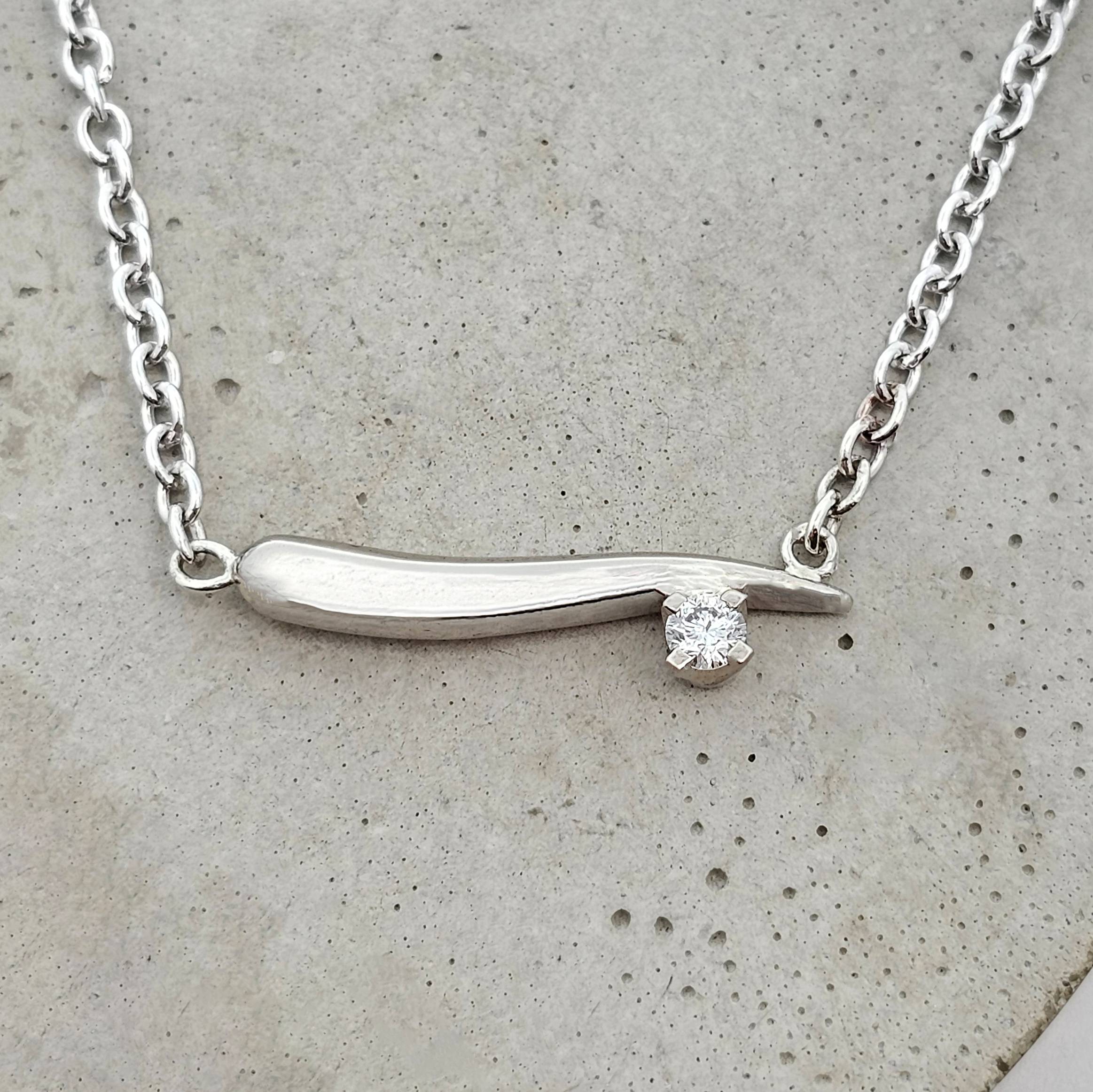 White gold diamond necklace with a sculpted curved bar and off-centre diamond. A modern gold necklace designed for effortless, everyday wear.