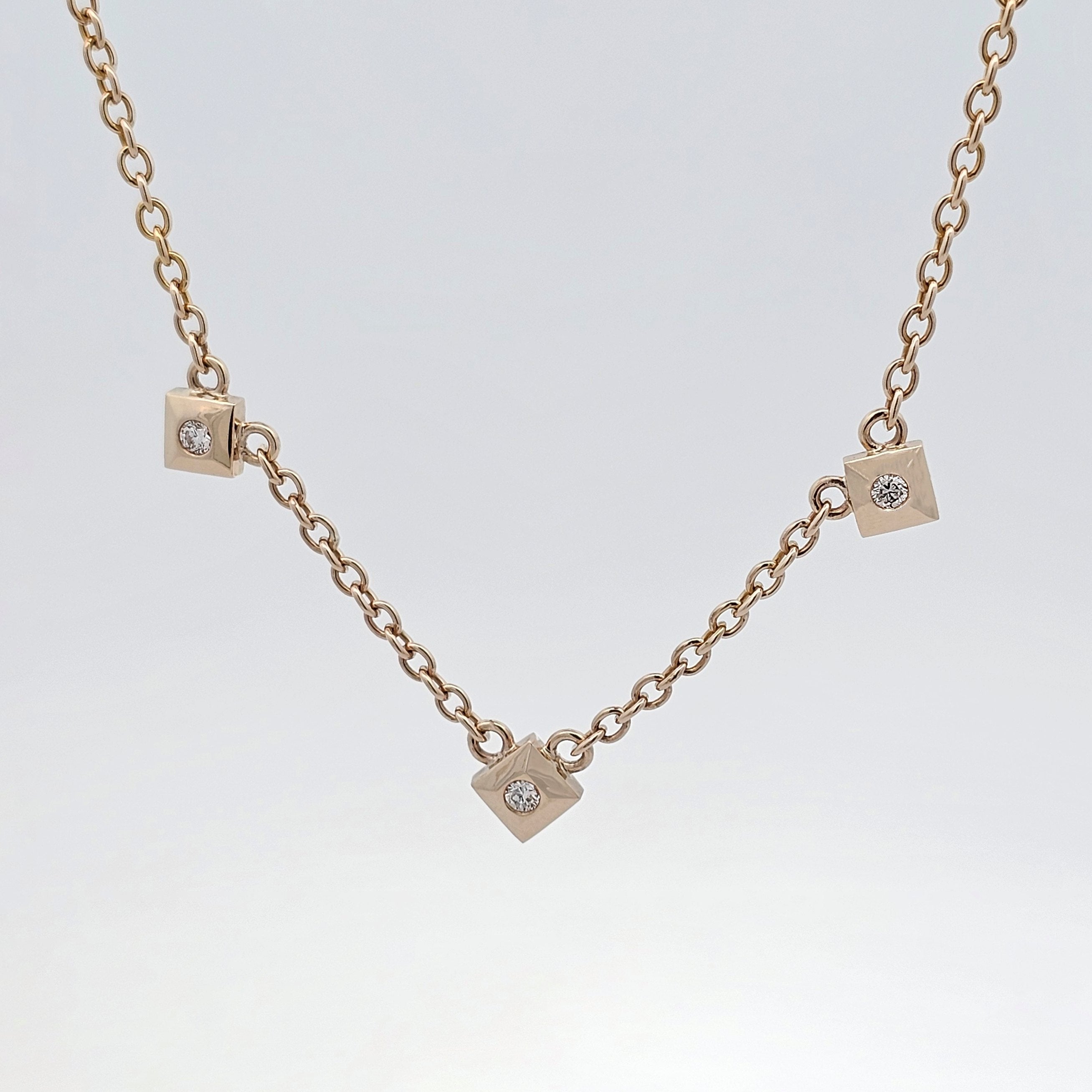 Yellow gold necklace with three petite diamond-set cube charms evenly spaced along a fine chain.