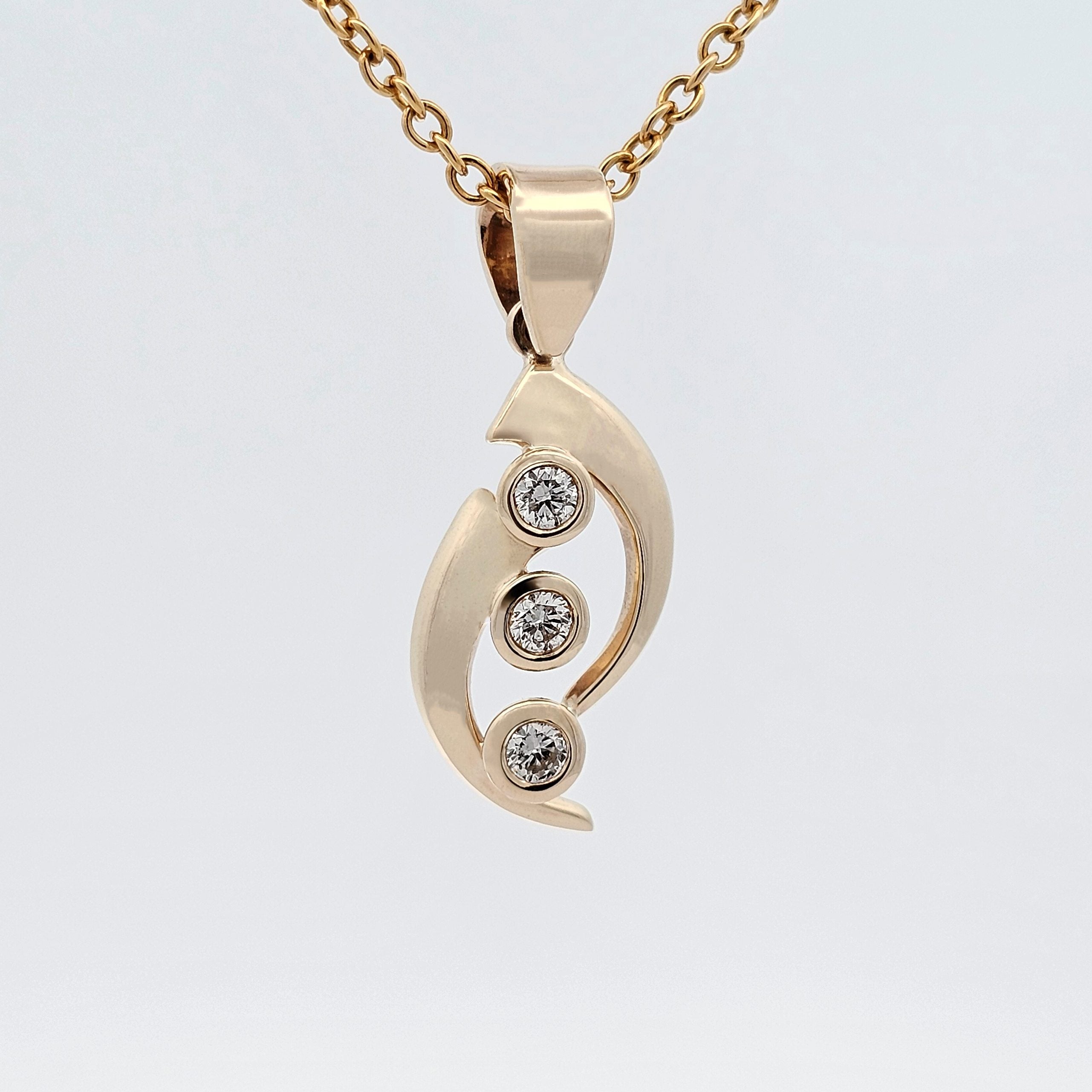 Yellow gold pendant featuring three bezel-set diamonds arranged vertically within soft curved shapes.